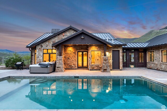 370 S Got Teeth Ln E, Emigration Canyon, UT 84108 - back of house at dusk featuring a standing seam roof, stone siding, and a patio