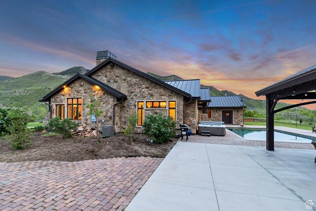 370 S Got Teeth Ln E, Emigration Canyon, UT 84108 - view of front facade featuring an outdoor hot tub, a standing seam roof, stone siding, a patio, and an outdoor pool