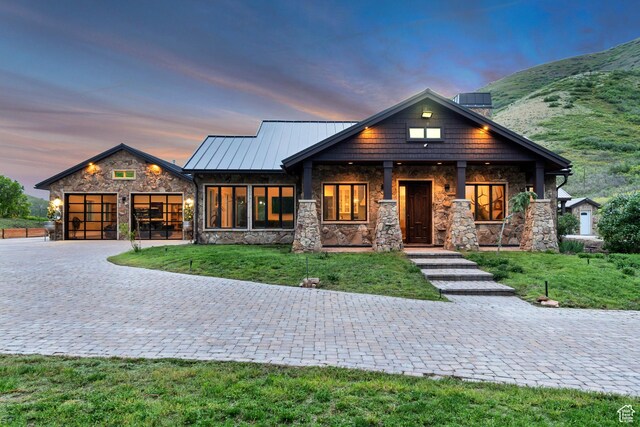 370 S Got Teeth Ln E, Emigration Canyon, UT 84108 - view of front of house with stone siding, decorative driveway, an attached garage, a front lawn, and a standing seam roof
