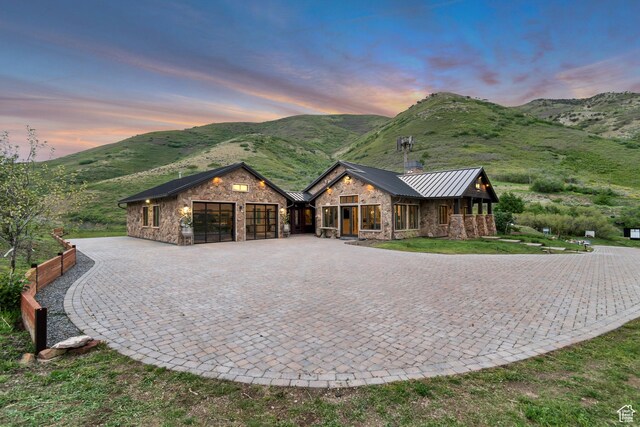 370 S Got Teeth Ln E, Emigration Canyon, UT 84108 - view of front facade featuring stone siding, a standing seam roof, a garage, a mountain view, and curved driveway