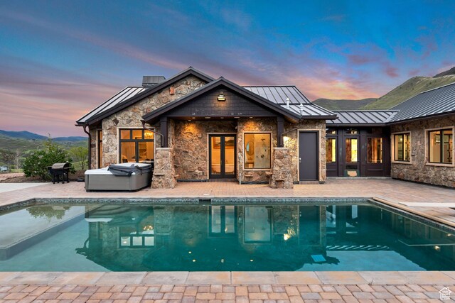 370 S Got Teeth Ln E, Emigration Canyon, UT 84108 - back of property at dusk with a standing seam roof, a patio, french doors, an outdoor pool, and a metal roof