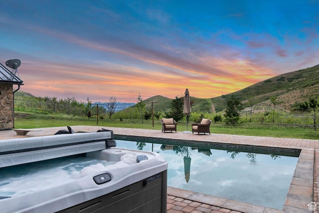 370 S Got Teeth Ln E, Emigration Canyon, UT 84108 - pool at dusk with a hot tub, a mountain view, an outdoor pool, a lawn, and a patio