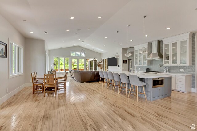 370 S Got Teeth Ln E, Emigration Canyon, UT 84108 - kitchen featuring wall chimney range hood, a chandelier, light wood finished floors, light countertops, and lofted ceiling