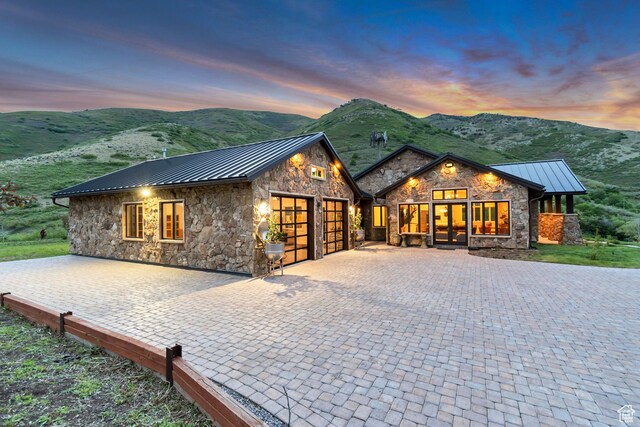 370 S Got Teeth Ln E, Emigration Canyon, UT 84108 - view of front of home with a standing seam roof, stone siding, a garage, a metal roof, and a mountain view