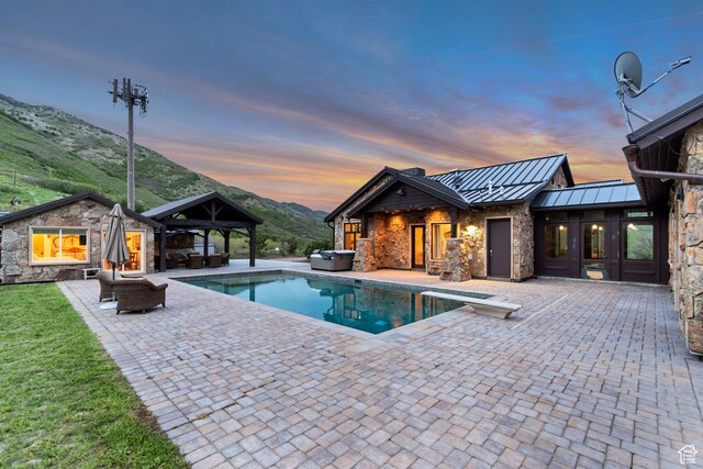 370 S Got Teeth Ln E, Emigration Canyon, UT 84108 - pool at dusk featuring a gazebo, a hot tub, a patio area, an outdoor pool, and a mountain view