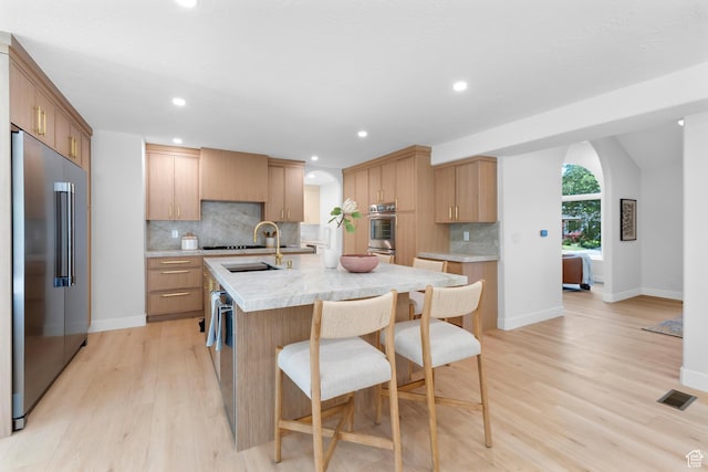 2795 E Palma Way, Cottonwood Heights, UT 84121 - kitchen with stainless steel appliances, light countertops, light wood-type flooring, tasteful backsplash, and a kitchen bar