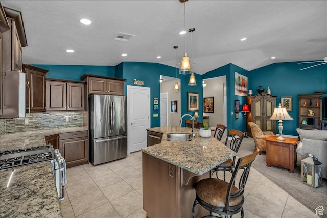 3075 E Delany Dr, St George, UT 84790 - kitchen featuring appliances with stainless steel finishes, vaulted ceiling, open floor plan, tasteful backsplash, and light tile patterned flooring