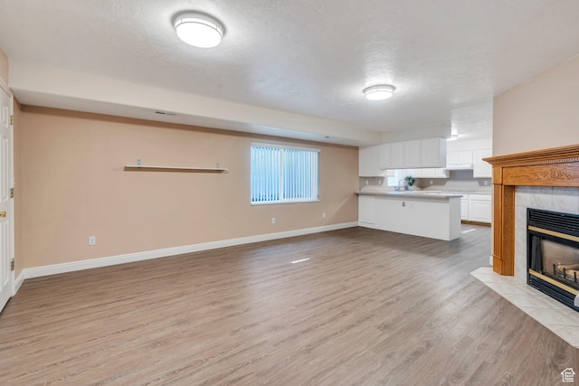 2522 N 1000 E, Provo, UT 84604 - unfurnished living room featuring a textured ceiling, a tile fireplace, and light wood-type flooring