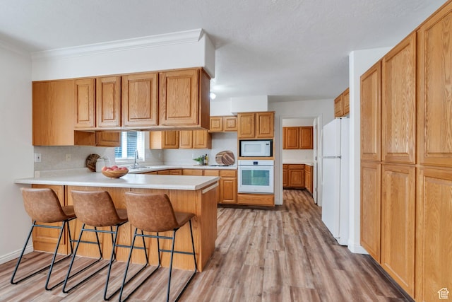2522 N 1000 E, Provo, UT 84604 - kitchen with white appliances, a peninsula, light wood-type flooring, a kitchen breakfast bar, and light countertops