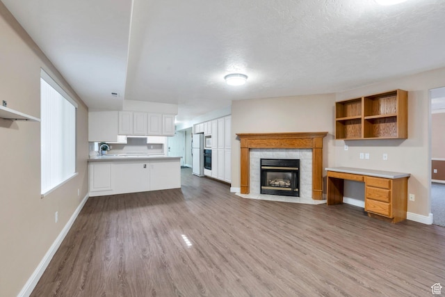 2522 N 1000 E, Provo, UT 84604 - unfurnished living room with wood finished floors, a tiled fireplace, and a textured ceiling