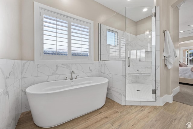 2530 S Monterosa Ln, St George, UT 84790 - bathroom with tile walls, connected bathroom, a shower stall, a soaking tub, and wood finished floors
