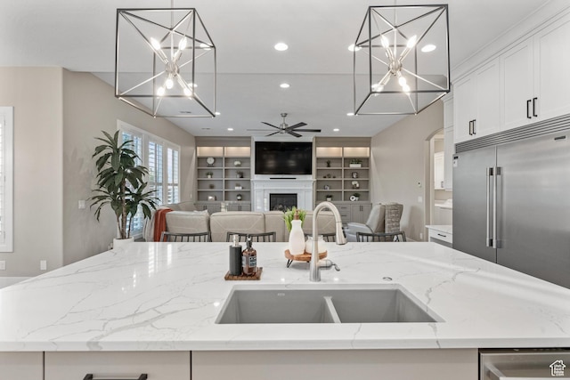 2530 S Monterosa Ln, St George, UT 84790 - kitchen featuring stainless steel appliances, open floor plan, a fireplace, white cabinetry, and light stone counters