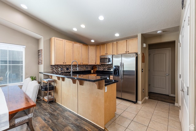 1150 N Wiltshire Dr W, North Salt Lake, UT 84054 - kitchen featuring appliances with stainless steel finishes, light brown cabinets, a peninsula, dark countertops, and recessed lighting