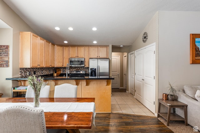 1150 N Wiltshire Dr W, North Salt Lake, UT 84054 - kitchen featuring appliances with stainless steel finishes, a peninsula, backsplash, light brown cabinetry, and dark countertops