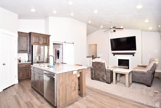 397 S Trejo Ridge Rd E, Grantsville, UT 84029 - kitchen featuring appliances with stainless steel finishes, vaulted ceiling, light wood-style flooring, open floor plan, and a center island with sink