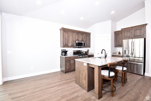 397 S Trejo Ridge Rd E, Grantsville, UT 84029 - kitchen featuring appliances with stainless steel finishes, light wood finished floors, an island with sink, light stone countertops, and lofted ceiling