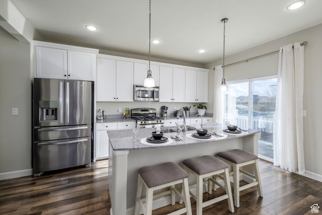 6459 N Star Discovery Way W, Stansbury Park, UT 84074 - kitchen featuring appliances with stainless steel finishes, white cabinetry, dark wood-style floors, recessed lighting, and a breakfast bar