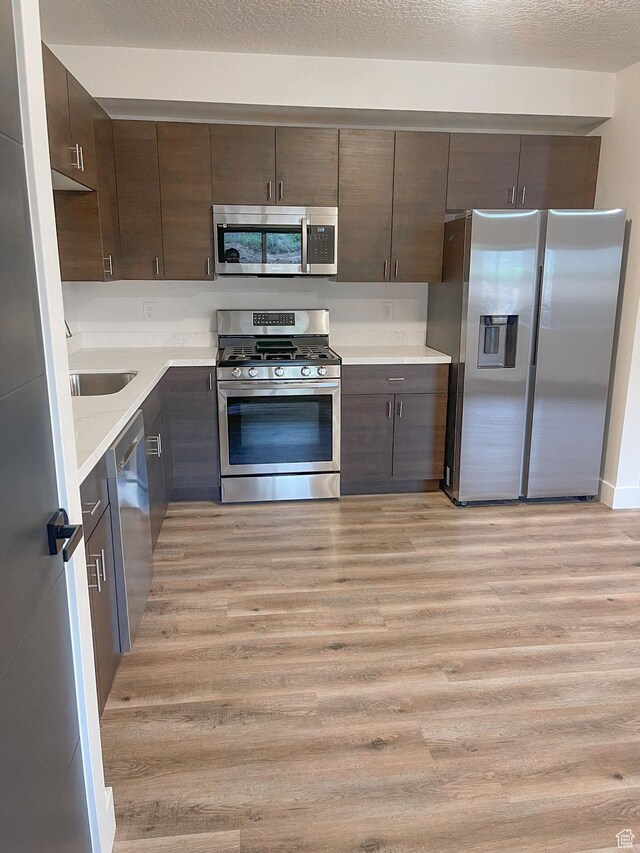 113 N 1400 E, Pleasant Grove, UT 84062 - kitchen with stainless steel appliances, light wood-style floors, dark brown cabinets, and light countertops