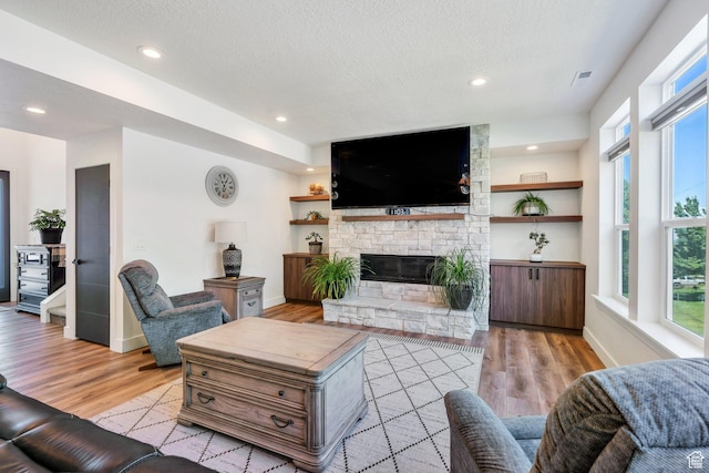 113 N 1400 E, Pleasant Grove, UT 84062 - living area with light wood-style floors, a stone fireplace, a textured ceiling, and recessed lighting