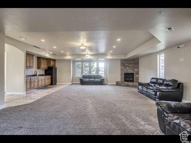 1045 S 1700 W Unit 320, Payson, UT 84651 - living area featuring light carpet, a tray ceiling, a stone fireplace, recessed lighting, and light tile patterned flooring