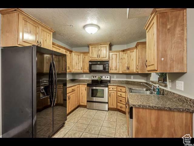 1045 S 1700 W Unit 320, Payson, UT 84651 - kitchen featuring black appliances, a textured ceiling, light brown cabinets, light tile patterned flooring, and dark countertops