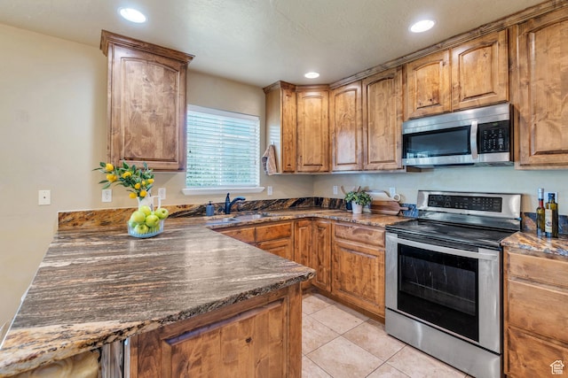 1198 N Reese Dr, Provo, UT 84601 - kitchen featuring stainless steel appliances, recessed lighting, light tile patterned flooring, brown cabinets, and dark stone counters