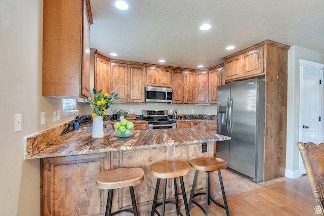 1198 N Reese Dr, Provo, UT 84601 - kitchen featuring stainless steel appliances, a peninsula, light wood-type flooring, recessed lighting, and a breakfast bar area