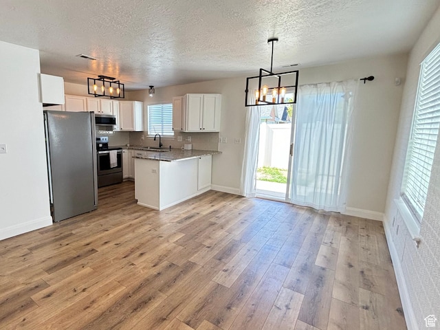 1165 N 2850 W, Provo, UT 84601 - kitchen featuring stainless steel appliances, a chandelier, a peninsula, white cabinetry, and light wood-style floors