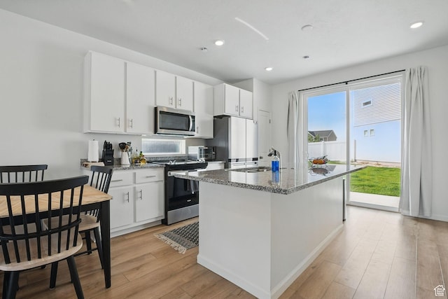 98 E Stroll Ave Unit 809, Saratoga Springs, UT 84045 - kitchen with appliances with stainless steel finishes, light wood-style flooring, a center island with sink, light stone counters, and recessed lighting