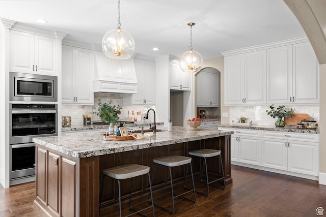 2209 E Viscaya Dr, Draper, UT 84020 - kitchen with appliances with stainless steel finishes, arched walkways, decorative backsplash, dark wood-style flooring, and recessed lighting