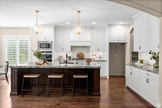2209 E Viscaya Dr, Draper, UT 84020 - kitchen featuring appliances with stainless steel finishes, arched walkways, decorative backsplash, a breakfast bar area, and recessed lighting