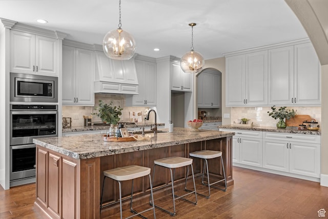2209 E Viscaya Dr, Draper, UT 84020 - kitchen featuring appliances with stainless steel finishes, backsplash, wood finished floors, arched walkways, and recessed lighting