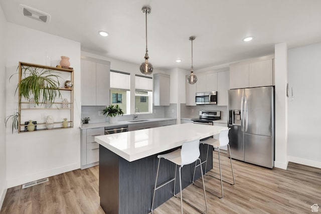 6366 W Sugarcane Dr S Unit 310, South Jordan, UT 84009 - kitchen with stainless steel appliances, a kitchen bar, backsplash, light countertops, and light wood-type flooring