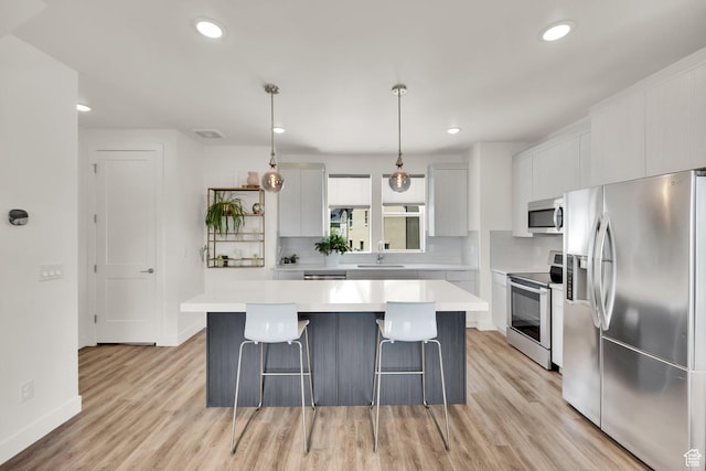 6366 W Sugarcane Dr S Unit 310, South Jordan, UT 84009 - kitchen with stainless steel appliances, a breakfast bar, a kitchen island, light wood-style flooring, and recessed lighting