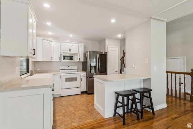 3285 W 6775 S, West Jordan, UT 84084 - kitchen with white appliances, recessed lighting, white cabinetry, a breakfast bar, and a peninsula