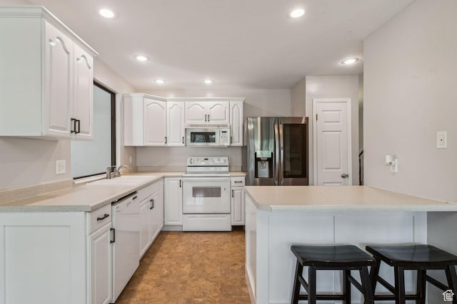 3285 W 6775 S, West Jordan, UT 84084 - kitchen with white appliances, a kitchen breakfast bar, a peninsula, white cabinets, and recessed lighting
