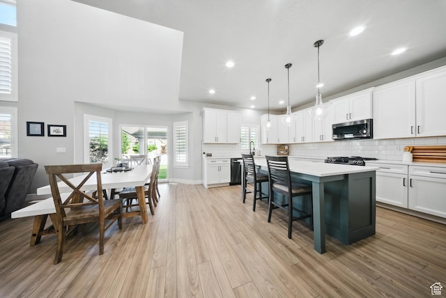 4888 W Transcendent Ct, West Jordan, UT 84081 - kitchen with stainless steel appliances, a kitchen bar, light countertops, light wood-type flooring, and decorative backsplash