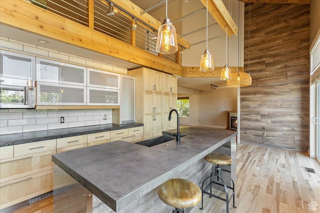 1794 E Longbranch Dr, Draper, UT 84020 - kitchen featuring a high ceiling, wood walls, dark countertops, light wood-style floors, and a kitchen bar