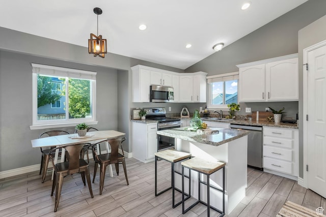 7839 N Apache Ln E, Eagle Mountain, UT 84005 - kitchen with appliances with stainless steel finishes, white cabinetry, vaulted ceiling, wood tiled floors, and light stone countertops