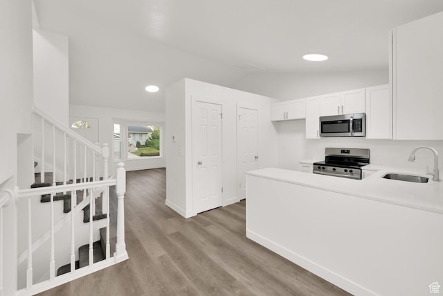 3042 W 8565 S, West Jordan, UT 84088 - kitchen with stainless steel appliances, light countertops, lofted ceiling, white cabinetry, and light wood finished floors