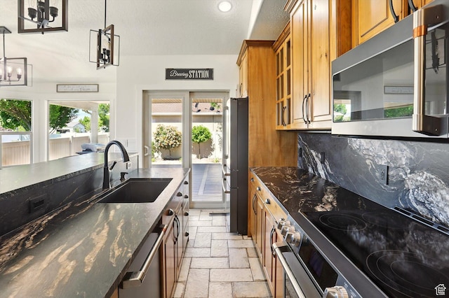 7414 S Regal Dr, West Jordan, UT 84081 - kitchen with appliances with stainless steel finishes, brown cabinets, stone tile floors, dark stone counters, and glass insert cabinets