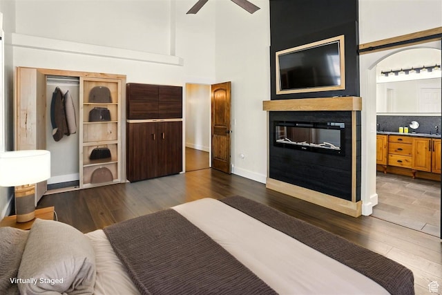 7414 S Regal Dr, West Jordan, UT 84081 - bedroom featuring dark wood-style flooring, a towering ceiling, and a glass covered fireplace