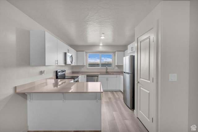 1167 E Telegraph St # A104, Washington, UT 84780 - kitchen featuring stainless steel appliances, a peninsula, light wood-type flooring, light countertops, and white cabinetry