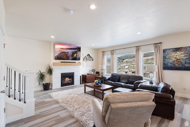 7982 N Bristlecone Rd, Eagle Mountain, UT 84005 - living area with light wood-style flooring, a tile fireplace, recessed lighting, and stairs