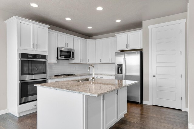 1298 E Salt Creek Peak, Eagle Mountain, UT 84005 - kitchen featuring appliances with stainless steel finishes, dark wood-style flooring, white cabinetry, a center island with sink, and tasteful backsplash