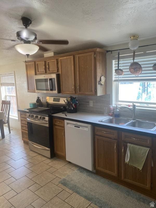 165 S 200th Ct W, Vernal, UT 84078 - kitchen with appliances with stainless steel finishes, a textured ceiling, healthy amount of natural light, tasteful backsplash, and brown cabinetry