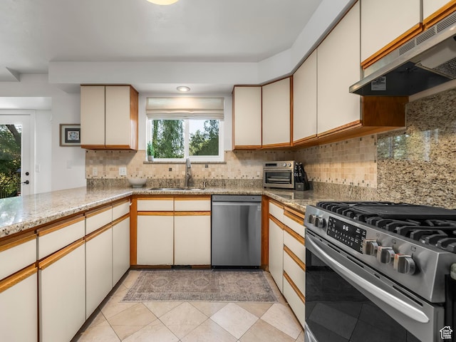 1705 E Plata Way, Sandy, UT 84093 - kitchen with appliances with stainless steel finishes, under cabinet range hood, backsplash, light stone counters, and light tile patterned floors