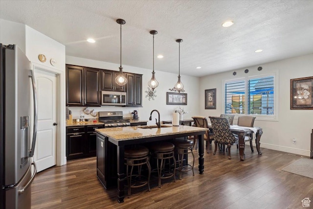2892 W 2500 N, Clinton, UT 84015 - kitchen featuring stainless steel appliances, a kitchen breakfast bar, dark wood-type flooring, light stone countertops, and a textured ceiling