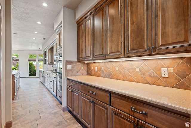 1285 Summerwood Cir, Santa Clara, UT 84765 - kitchen with recessed lighting, a textured ceiling, tasteful backsplash, stainless steel oven, and light stone countertops