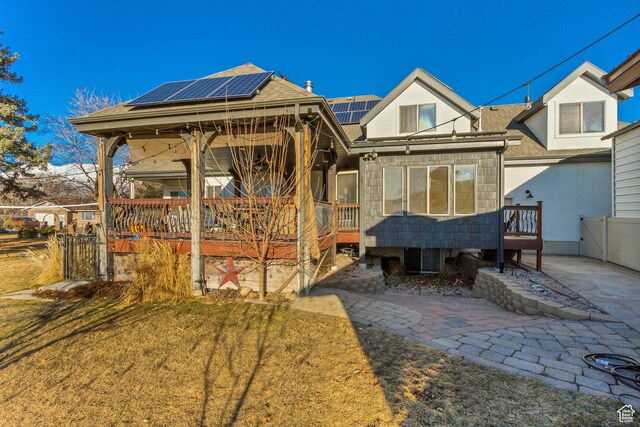 338 S Holdaway Rd, Vineyard, UT 84059 - back of house featuring roof mounted solar panels, roof with shingles, stucco siding, and a wooden deck